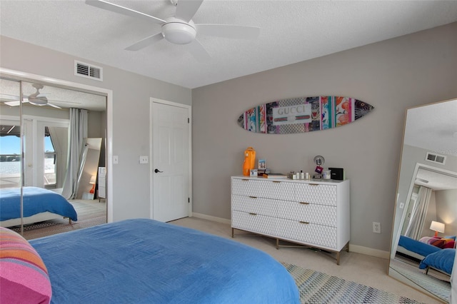 bedroom featuring a textured ceiling, ceiling fan, and light carpet