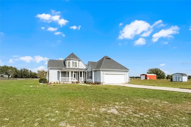 view of front of home featuring a shed, a garage, a front yard, and covered porch