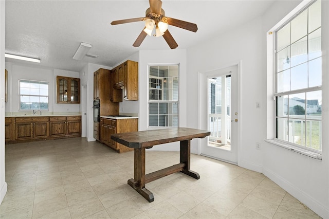 kitchen featuring gas stovetop, sink, oven, and ceiling fan