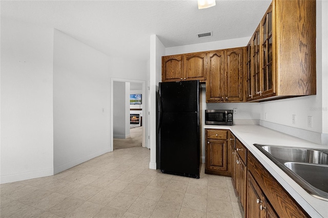 kitchen with black fridge, sink, and a textured ceiling