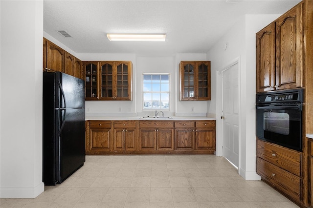 kitchen with sink, black appliances, and a textured ceiling