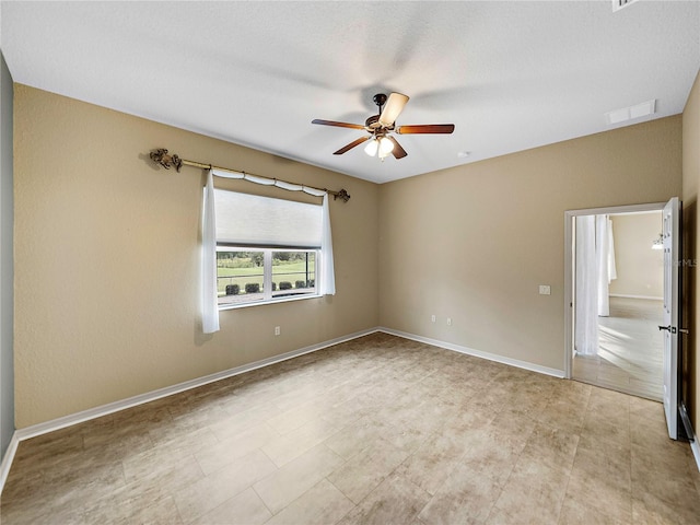 empty room featuring ceiling fan, visible vents, and baseboards