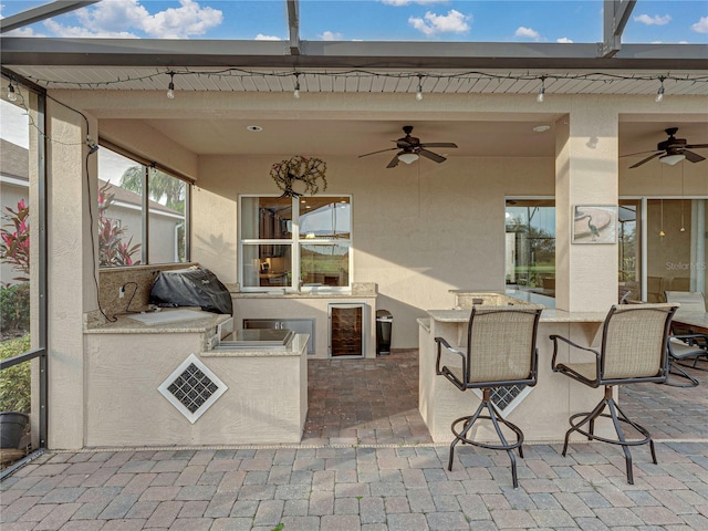 view of patio with beverage cooler, an outdoor kitchen, outdoor wet bar, and a ceiling fan