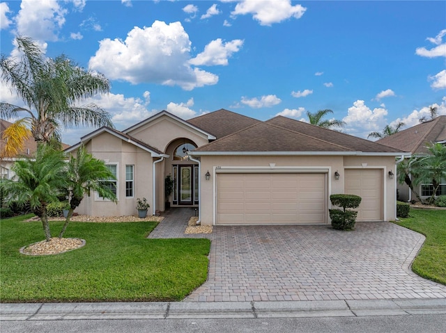 single story home featuring a garage, a front yard, decorative driveway, and stucco siding