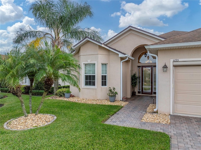 view of front of property featuring a front lawn, an attached garage, and stucco siding