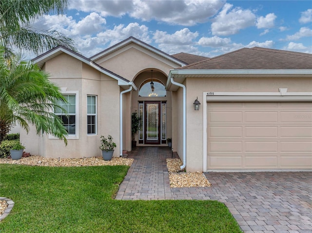 single story home featuring a shingled roof, a front lawn, an attached garage, and stucco siding