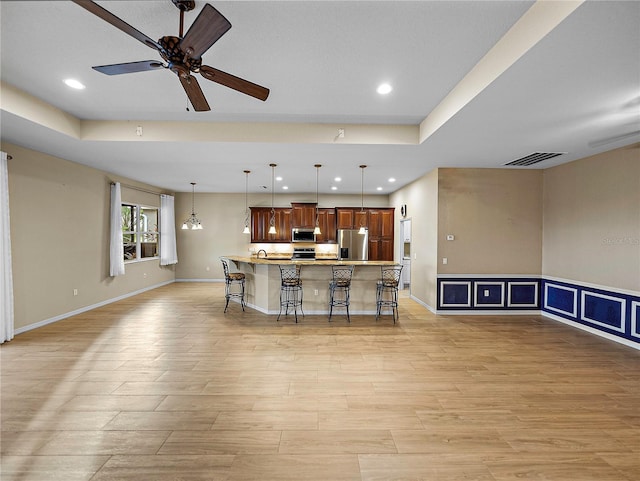 kitchen featuring stainless steel appliances, a breakfast bar, visible vents, open floor plan, and pendant lighting