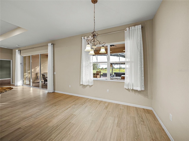 unfurnished dining area with light wood-type flooring, baseboards, and an inviting chandelier