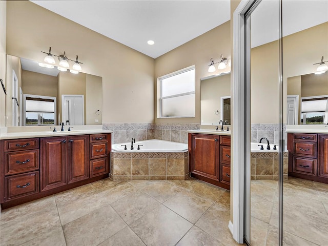 full bathroom featuring a garden tub, two vanities, a sink, and tile patterned floors