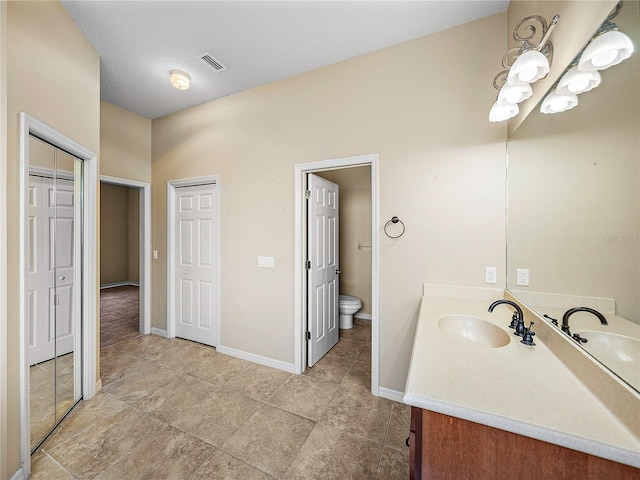 bathroom with toilet, baseboards, visible vents, and vanity