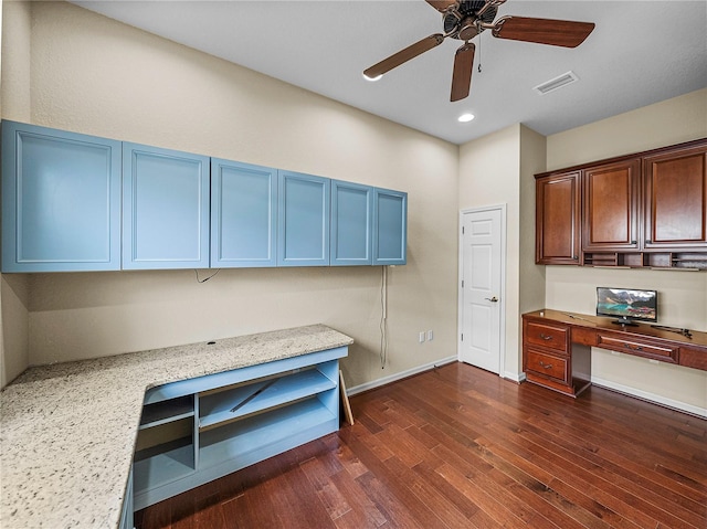 unfurnished office with baseboards, visible vents, a ceiling fan, built in study area, and dark wood-type flooring