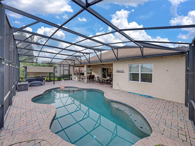 outdoor pool with ceiling fan, a patio, a lanai, and a hot tub