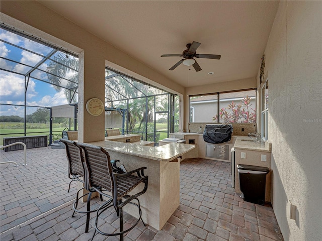 sunroom featuring ceiling fan and a sink