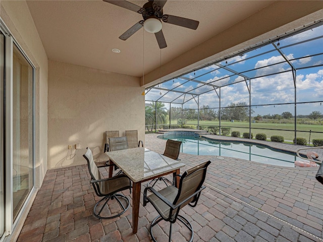 view of patio / terrace with a ceiling fan, glass enclosure, and an outdoor pool