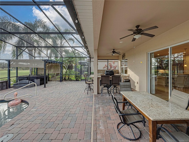 view of patio / terrace with outdoor dry bar, glass enclosure, a ceiling fan, and a hot tub