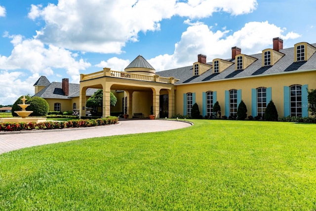 view of front of home featuring a front yard, driveway, a chimney, and stucco siding