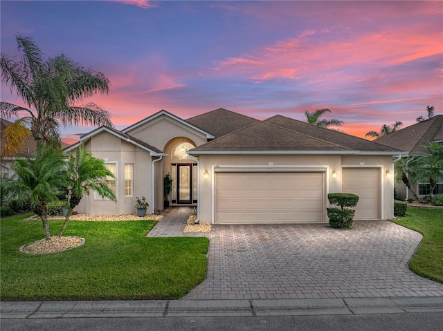 single story home featuring decorative driveway, stucco siding, a shingled roof, an attached garage, and a front yard