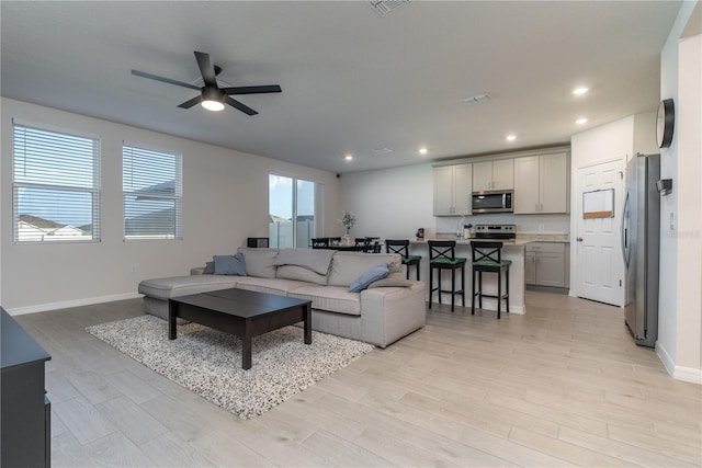 living room with ceiling fan and light wood-type flooring