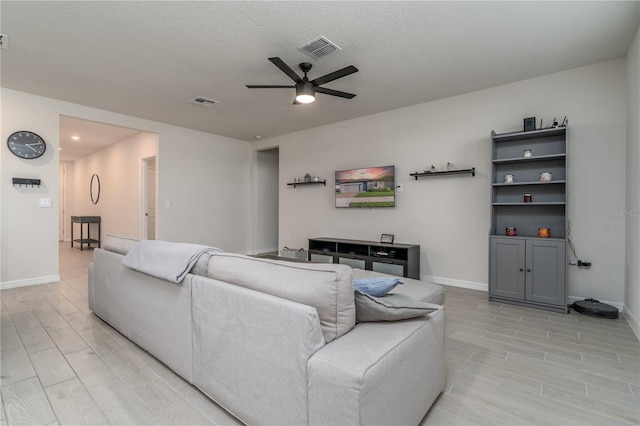 living room with a textured ceiling, light hardwood / wood-style floors, and ceiling fan