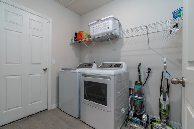 washroom featuring washing machine and clothes dryer and light hardwood / wood-style floors