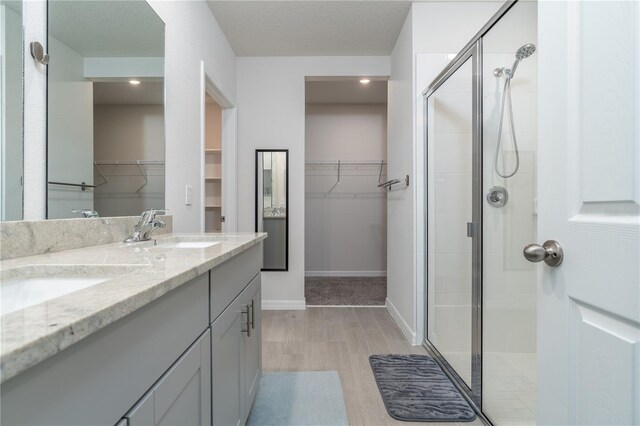 bathroom featuring walk in shower, vanity, a textured ceiling, and hardwood / wood-style flooring