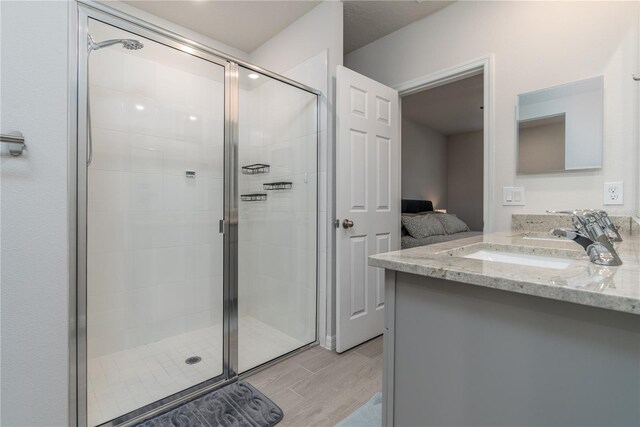 bathroom featuring vanity, wood-type flooring, and a shower with shower door