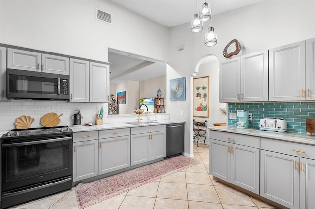 kitchen with gray cabinetry, sink, light tile patterned floors, and appliances with stainless steel finishes