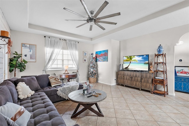 living room featuring ceiling fan, light tile patterned floors, and a tray ceiling