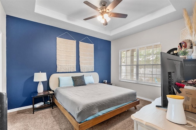 bedroom featuring ceiling fan, carpet floors, and a tray ceiling