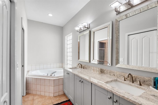 bathroom featuring vanity, tile patterned flooring, and a relaxing tiled tub