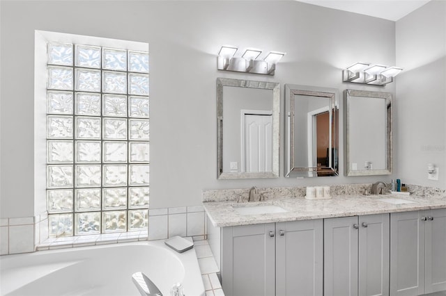 bathroom featuring vanity, a healthy amount of sunlight, and tiled tub