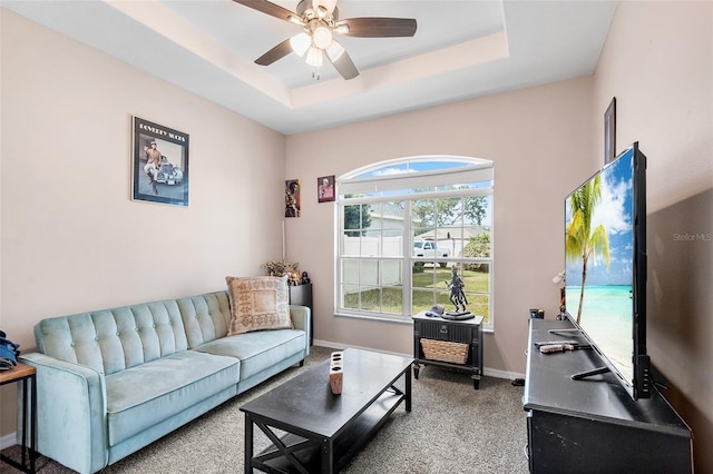 carpeted living room with ceiling fan and a tray ceiling