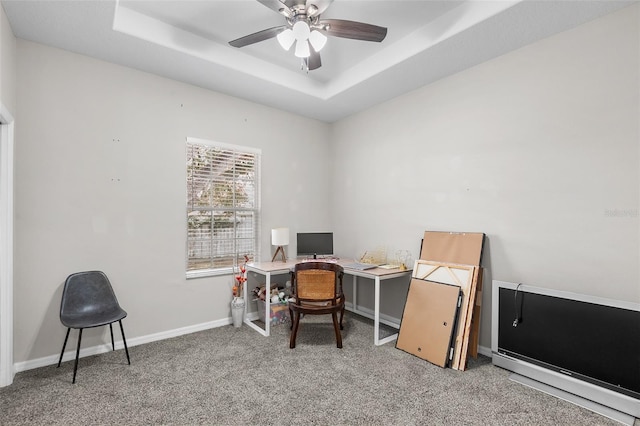 carpeted office featuring ceiling fan and a raised ceiling