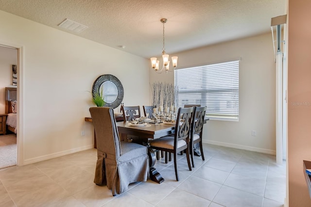 dining area with a textured ceiling, a notable chandelier, and light tile patterned flooring