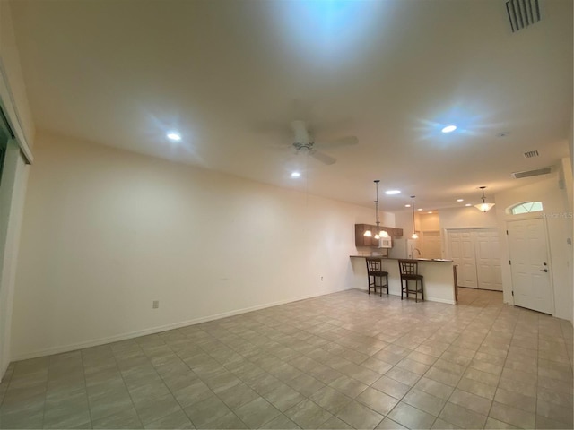 unfurnished living room featuring ceiling fan and indoor bar