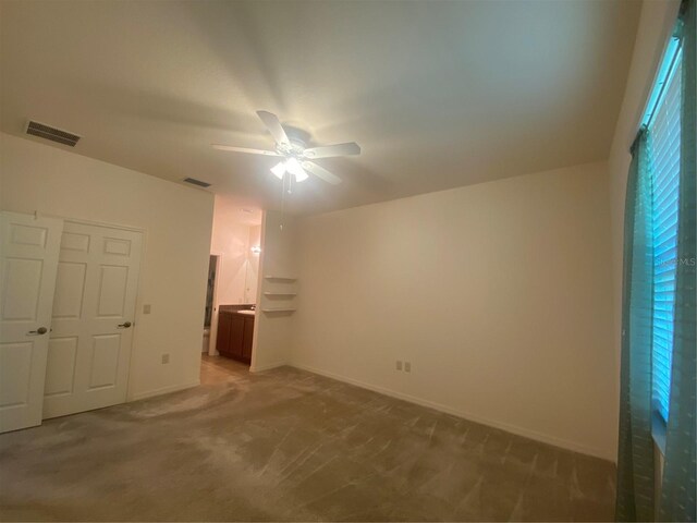 unfurnished bedroom with carpet flooring, ensuite bath, ceiling fan, and a closet