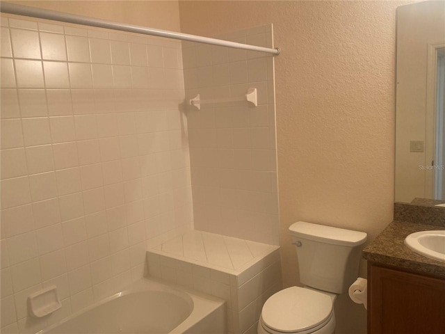 full bathroom featuring tiled shower / bath, vanity, and toilet