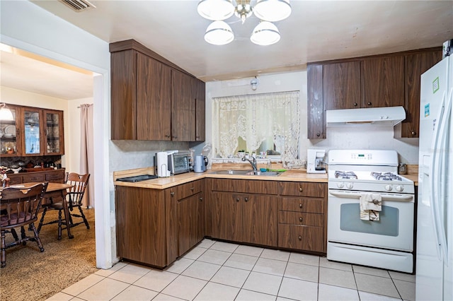 kitchen featuring dark brown cabinetry, sink, and white appliances