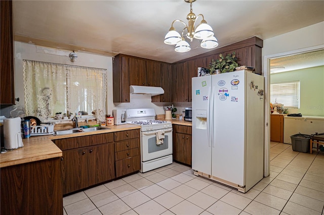 kitchen with dark brown cabinetry, sink, an inviting chandelier, decorative light fixtures, and white appliances