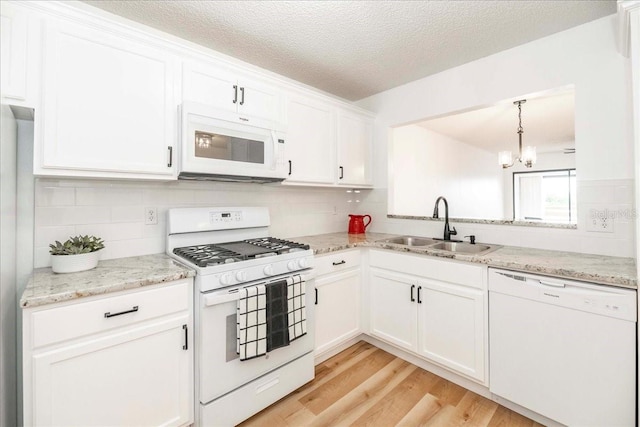 kitchen featuring white appliances, sink, light hardwood / wood-style floors, white cabinetry, and a chandelier