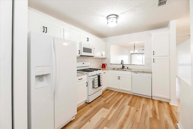 kitchen with white cabinetry, sink, light hardwood / wood-style flooring, a notable chandelier, and white appliances