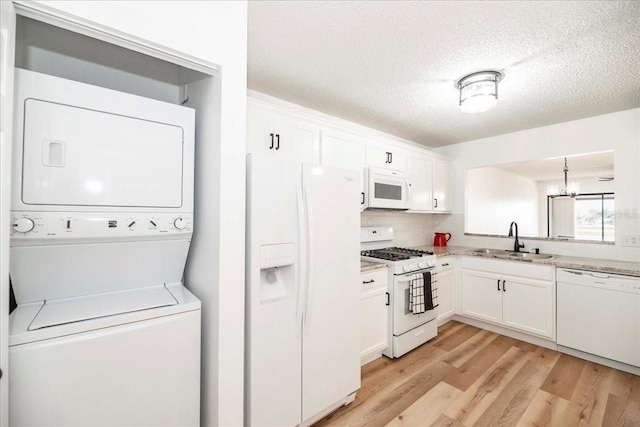 kitchen with white cabinetry, white appliances, sink, and stacked washer and clothes dryer