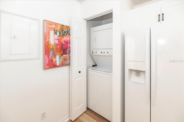 washroom with stacked washer / dryer, electric panel, and light hardwood / wood-style flooring