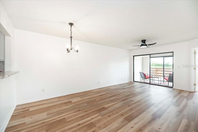 unfurnished living room with ceiling fan with notable chandelier and light hardwood / wood-style floors