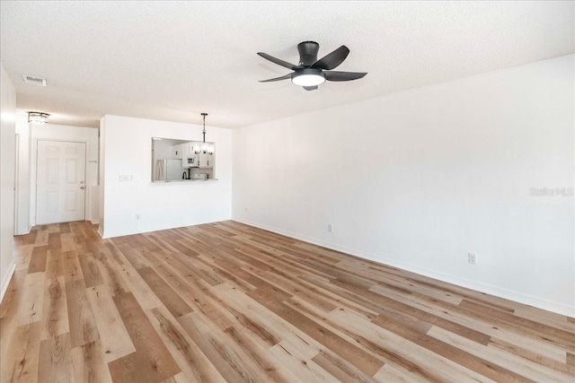 unfurnished living room featuring ceiling fan with notable chandelier, a textured ceiling, and light hardwood / wood-style floors