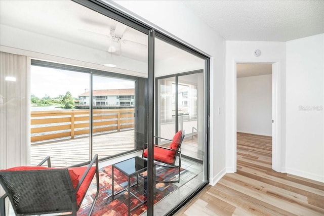 doorway to outside with a wealth of natural light, light hardwood / wood-style flooring, and a textured ceiling