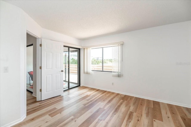 unfurnished room with light hardwood / wood-style flooring and a textured ceiling