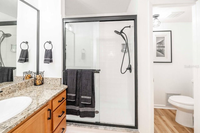 bathroom with hardwood / wood-style floors, vanity, toilet, and walk in shower