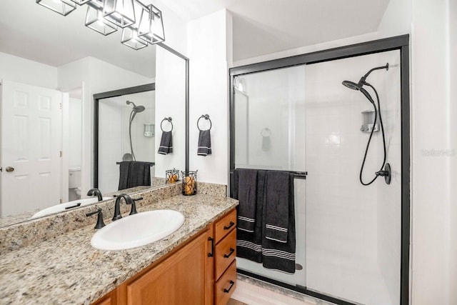 bathroom featuring a shower with door and vanity