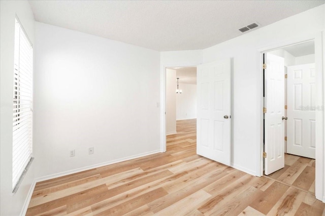 unfurnished bedroom with light wood-type flooring and a textured ceiling